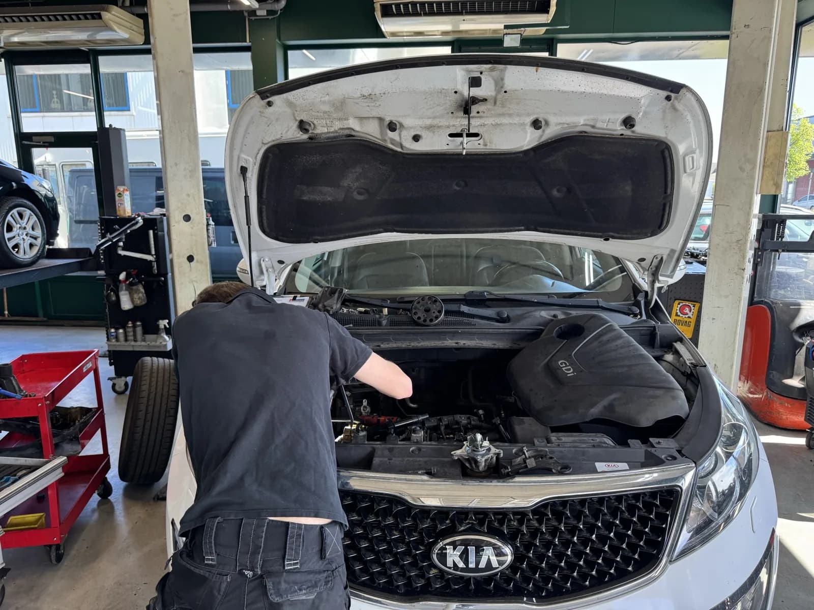 KIA onderhoud Alkmaar — onderhoud alle merken bij MTechniek Monteur van MTechniek werkt aan motor van een witte KIA tijdens onderhoud in werkplaats Alkmaar